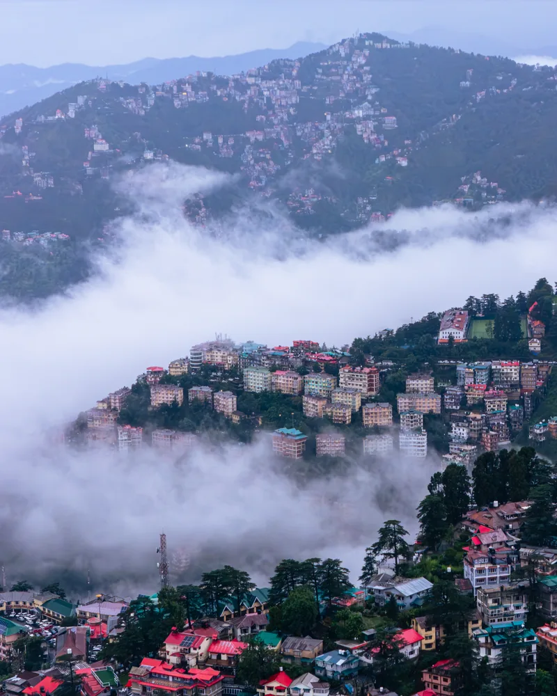 Hillside buildings emerging above a thick bank of low cloud.